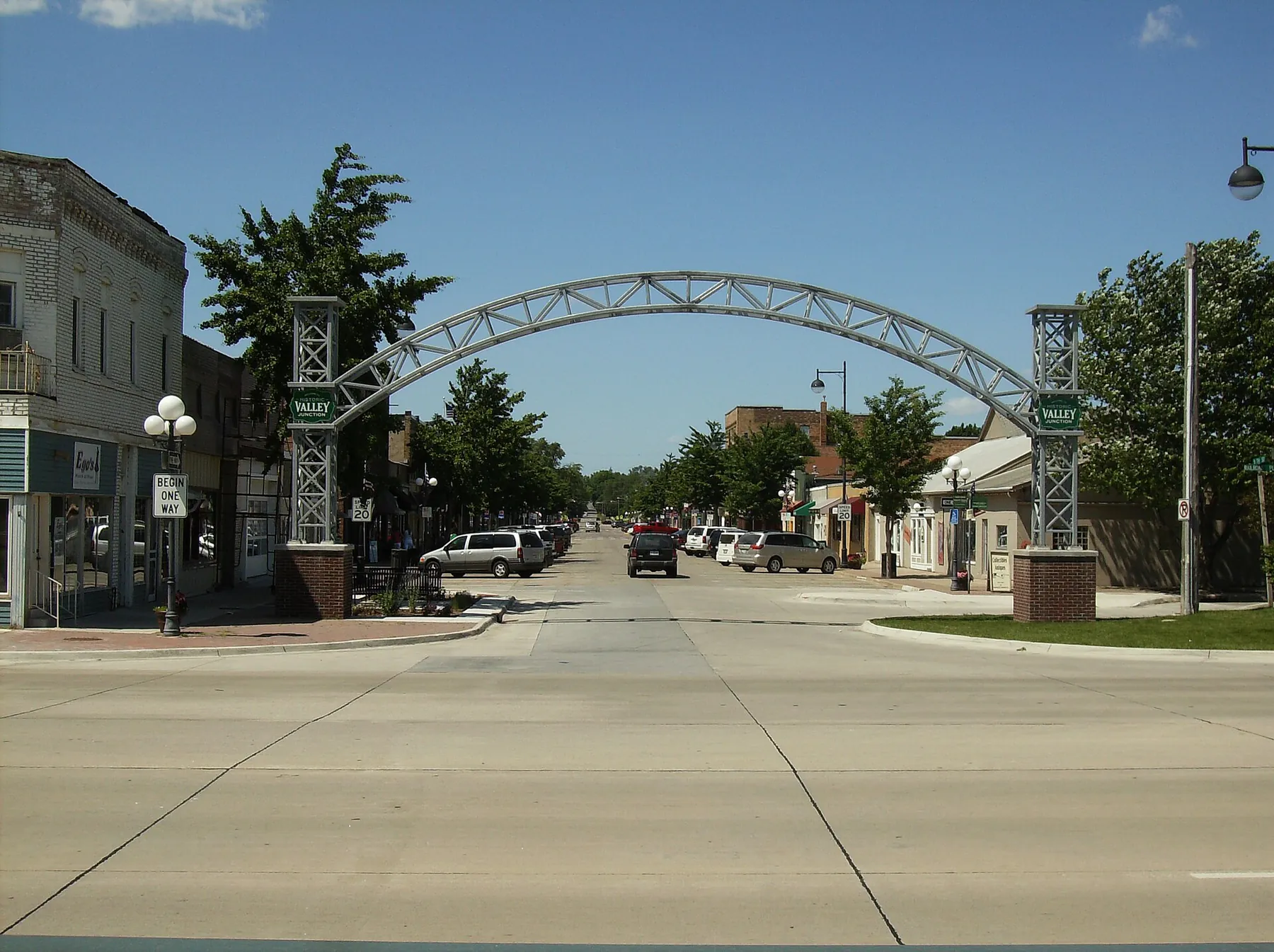 A steel arch spans the main street of Historic Valley Junction, lined with low brick storefronts and trees